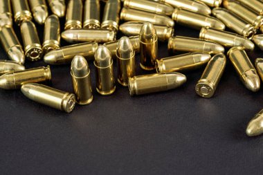 Siyah masadaki çok sayıda pirinç tabanca mermisi yakın çekim görüntüsü, metin alt kısmı için boşluk