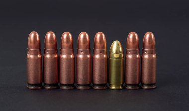 Siyah tahtada yan yana dizilmiş bronz tabanca mermileri.