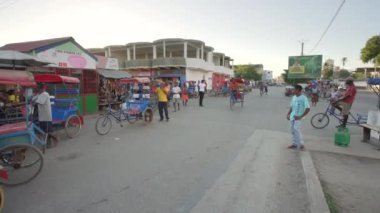 Toliara, Madagaskar - 01 Mayıs 2019: Meşgul kavşakta tipik bir akşam manzarası, insanlar yürüyor, bisikletli fayton geçiyor, yakınlarda araba sürüyor, market durakları var