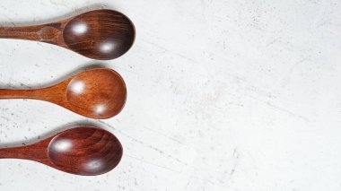 Small spoons made of dark wood, on white working board, view from above, space for text right side