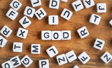 Tahtadaki küçük beyaz ve siyah boncuk küpleri, ortadaki harfler Tanrı, din kavramı.