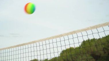 Plaj voleybol ağına, temiz gökyüzüne, gökkuşağı renkli topa bakıyorum.