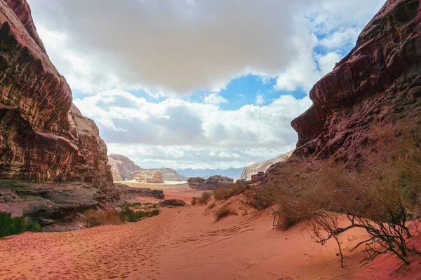 Rocky canyon with red sand on ground, blue sky in distance - Wadi Rum scenery