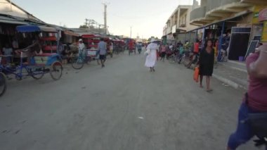Toliara, Madagaskar - 01 Mayıs 2019: Akşamları tipik orta büyüklükteki bir kasaba caddesinde yürümek, her iki tarafta market tezgahları, Malagasy 'li insanlar yürüyor, bazıları bisiklet sürüyor