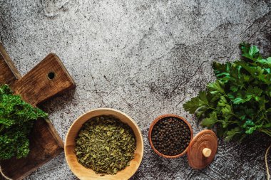 Taze kokulu çiftlik yeşili ve kurutulmuş maydanoz, gri beton arka planda bezelyeler. Metin için yer, üst görünüm