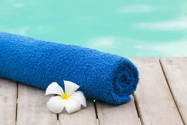 Serviette bleue et fleur au bord de la piscine — Photo