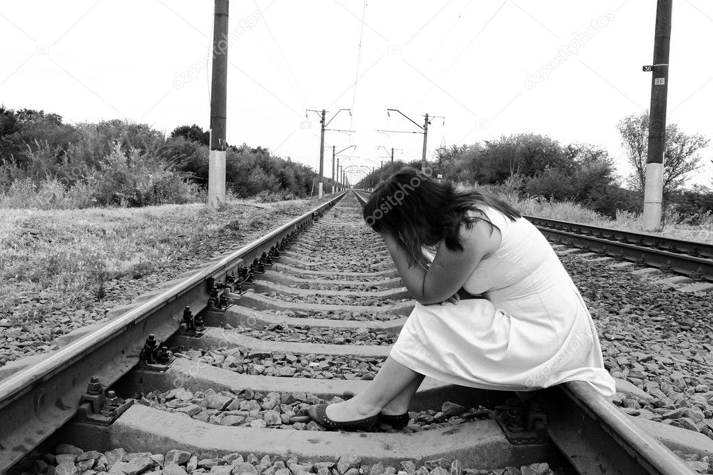 Pensive, sad woman sitting on railroad tracks — Stock Photo