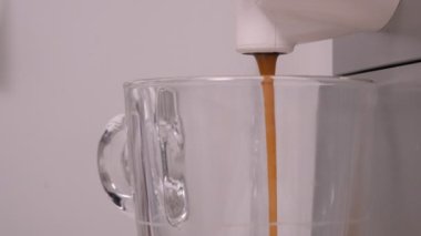 Kahve makinası, şeffaf cam bardağa kahve dolduruyor. Pastel nötr renkler, kapsüllü kahve.. 