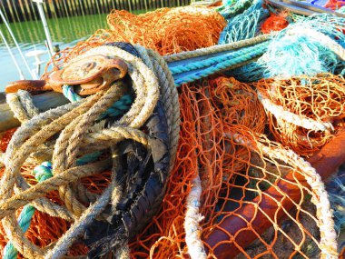 Sarı, paslı ve mavi demirleme çizgileri. Balık ağları, balıkçılık endüstrisi, eski halat ve paslı metal makara sistemi balıkçı teknesinin parçaları.