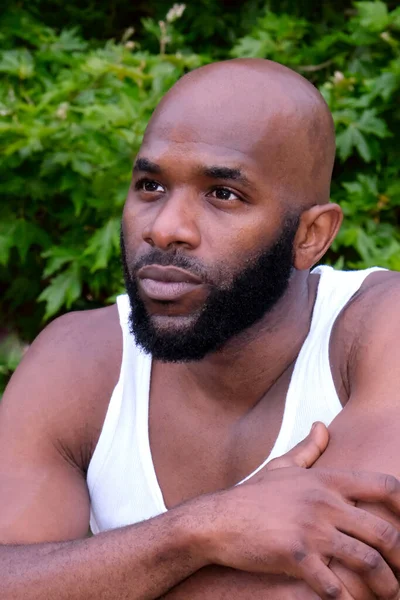 Middle age well build of Afro American man portrait close up wearing a white sleeveless T-shirt. Athletic build young man with a beard