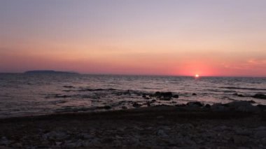 a beautiful sunset on the seaside with horizon line. A sun just about to disappear from the sky and calm waves on the sea side, Sicily, Italy