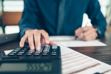 Finans işadamı, şirketlerin vergi vergilerini hesaplamak ve finansal tabloları analiz etmek için hesap makinesi kullanıyor. finans ve muhasebe kavramı.
