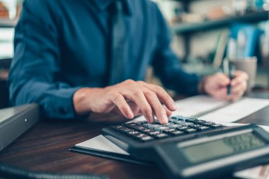 Finans işadamı, şirketlerin vergi vergilerini hesaplamak ve finansal tabloları analiz etmek için hesap makinesi kullanıyor. finans ve muhasebe kavramı.