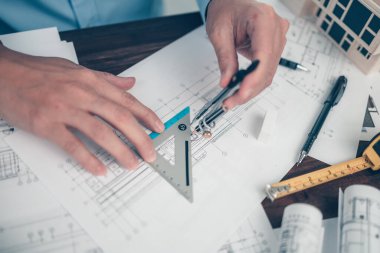 Architect engineer use compass and  triangular angle ruler  drawing design working on bueprint. House planning design and construction concept.