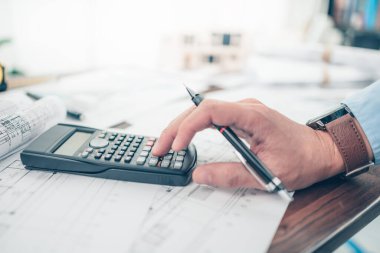 Mimar mühendis bueprint üzerinde çalışan çizim tasarımını hesaplamak için hesap makinesi kullanır. Ev planlama ve inşaat konsepti.