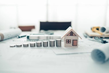 Mini model ev ve bozuk para yığını, bina planındaki merdiven gibi. Maliyet Mimarı ve Mühendislik kavramı.