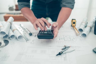 Mimar mühendis bueprint üzerinde çalışan çizim tasarımını hesaplamak için hesap makinesi kullanır. Ev planlama ve inşaat konsepti.