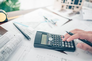 Mimar mühendis bueprint üzerinde çalışan çizim tasarımını hesaplamak için hesap makinesi kullanır. Ev planlama ve inşaat konsepti.