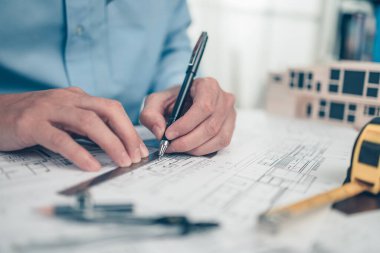 Mimar mühendis bueprint üzerinde çalışırken kalem ve açı koruyucu çizim tasarımı kullanır. Ev planlama ve inşaat konsepti.