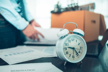 Masadaki çalar saat ve işsizler evrak ve dizüstü bilgisayarı karton kutuya koyun. İşten ayrılan işadamı, ya kovuldu ya da işten atıldı.