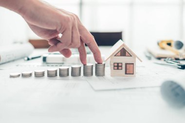 Mini model ev ve bozuk para yığını, bina planındaki merdiven gibi. Maliyet Mimarı ve Mühendislik kavramı.