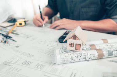 Yuvarlak planlı mini model ev ve mimar plan üzerinde kalem çizimi kullanıyor. Ev Mimarı tasarımı ve mühendisi konsepti.