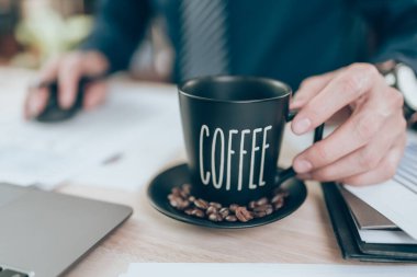 Muhasebeci bir fincan kahve tutuyor ve şirket verileri, belgeler ve masa başı raporları üzerinde çalışıyor. Muhasebe iş konsepti.