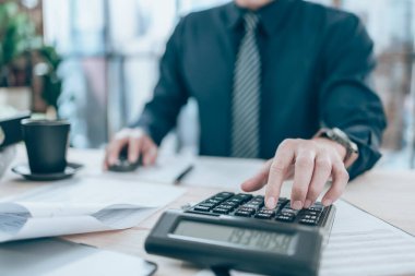 Şirket verilerini, belgelerini ve raporlarını masa başında hesaplamak için hesap makinesi üzerinde çalışan bir muhasebeci. Muhasebe iş konsepti.