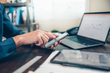 İş adamı cep telefonu kullanır ve ofis masasında çalışır ve yeni muhasebe finans projesini analiz eder. Yatırım, Mali Danışmanlık ve Muhasebe Konsepti.