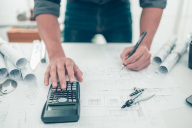 Mimar mühendisi, plan üzerinde çalışan çizim tasarımını hesaplamak için hesap makinesi kullanır. Ev planlama ve inşaat konsepti.
