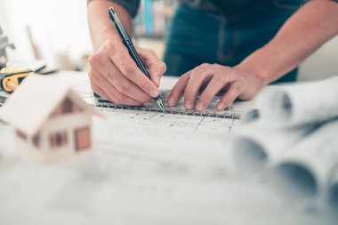 Mimar mühendis, plan üzerinde çalışırken kalem ve açı koruyucu çizim kullanıyor. Ev planlama ve inşaat konsepti.