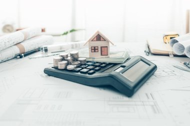Mini model ev ve hesap makinesinde bozuk para. Maliyet Mimarı ve Mühendislik kavramı.