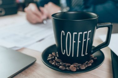 Ofis masasında bir fincan kahve ve hesap makinesi üzerinde çalışan muhasebeci şirket verilerini, belgelerini ve raporlarını masabaşında hesaplıyor. Muhasebe iş konsepti.