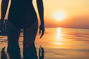 Yaz tatilinde, gün batımı manzaralı havuzda bir kadın silueti.. 