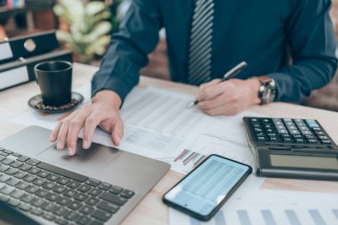 Şirket verilerini, belgelerini ve raporlarını masa başında hesaplamak için hesap makinesi üzerinde çalışan bir muhasebeci. Muhasebe iş konsepti.