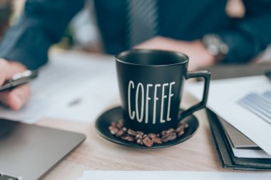 Ofis masasında bir fincan kahve ve hesap makinesi üzerinde çalışan muhasebeci şirket verilerini, belgelerini ve raporlarını masabaşında hesaplıyor. Muhasebe iş konsepti.