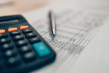 Masa başında kalem ve hesap makinesi var. Hesap makinesinin denge, projeksiyon, para ve maliyeti hesaplaması için nesne. Muhasebe ve Finans kavramı.