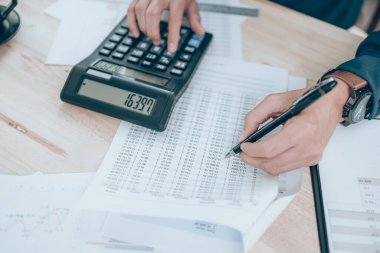 Masa başında hesaplamak için şirket verileri, belgeleri, raporları ve hesap makineleri üzerinde çalışan muhasebeci. Muhasebe iş konsepti.