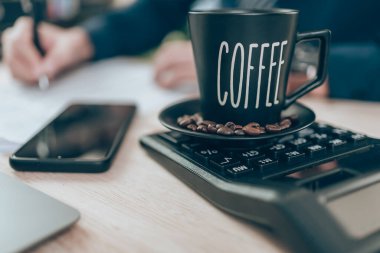 Cup of coffee on calculator and Accountant working on calculator to calculate company data, document and report on desk office. Accounting business concept.