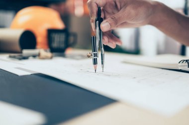 Bölücü pusula kullanan mimar plan üzerinde çalışıyor ve deftere not alıyor. İnşaat konsepti. Mühendislik araçları