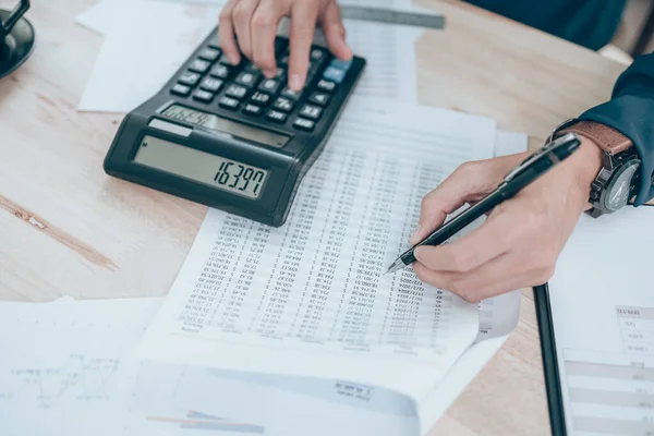 Masa başında hesaplamak için şirket verileri, belgeleri, raporları ve hesap makineleri üzerinde çalışan muhasebeci. Muhasebe iş konsepti.