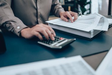 Masa başında çalışan yatırımcılar denge, kar, para ve maliyeti hesaplamak için hesap makinesi kullanıyorlar. Muhasebe ve Finans kavramı.