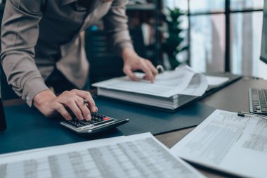 Masa başında çalışan yatırımcılar denge, kar, para ve maliyeti hesaplamak için hesap makinesi kullanıyorlar. Muhasebe ve Finans kavramı.