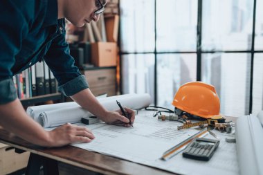 Mühendislik büro masasında çizimler, hesap makinesi, üçgen cetvel, güvenlik gözlüğü, pusula, mavi kalem. Mühendis, Mimar, Endüstri ve Fabrika Konsepti.