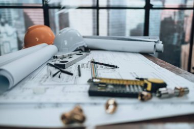 Engineering working with drawings inspection on the office desk and Calculator, triangle ruler, safety glasses, compass, vernier caliper on Blueprint. Engineer, Architect, Industry and factory concept.