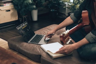 Genç adam evdeki oturma odasında kanepede otururken rahatlayıp gitar çalıyor. Müzik melodi, dizüstü bilgisayarda sözler ve pratik konsepti yaratır.