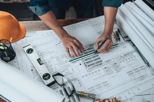 Engineering working with drawings inspection and writing on the office desk and Calculator, triangle ruler, safety glasses, compass, vernier caliper on Blueprint. Engineer, Architect, Industry and factory concept.