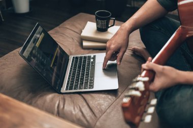 Genç adam evdeki oturma odasında kanepede otururken rahatlayıp gitar çalıyor. Müzik melodi, dizüstü bilgisayarda sözler ve pratik konsepti yaratır.