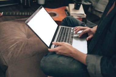  Müzik yapımcısı, evdeki oturma odasında kanepede otururken dizüstü bilgisayarda melodi ve şarkı sözleri yarattı..