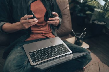 Erkekler müzik yapımcısının melodisini kontrol etmek için evdeki kanepede müzik dinlemek için kulaklık tutuyorlar. Rahat ev kavramı.